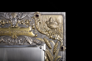 Close up detail of jewelry box cover corner featuring golden relief of game birds in tall grass.