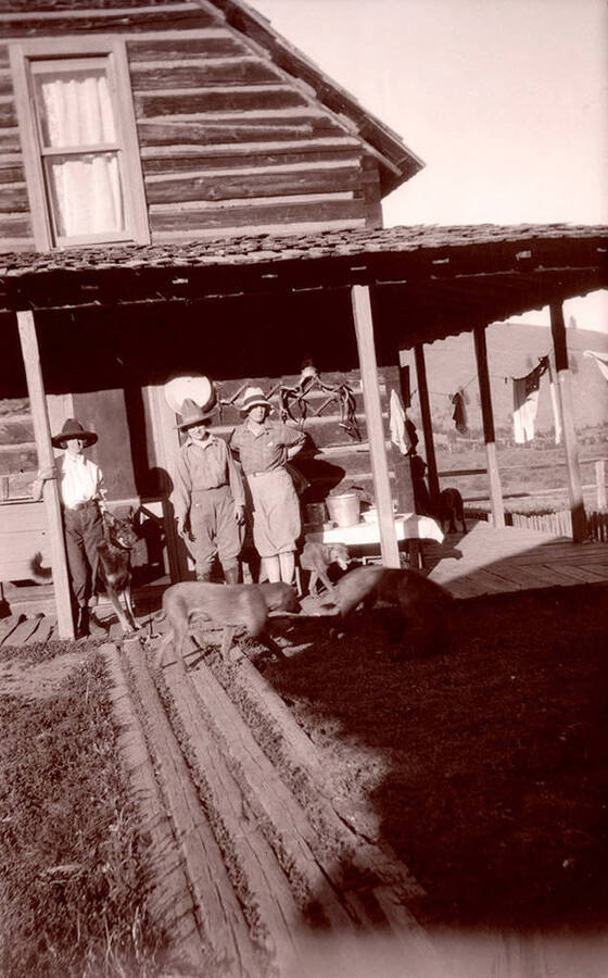Three women and five dogs stand on the wrap around porch of the Stonebraker Ranch.