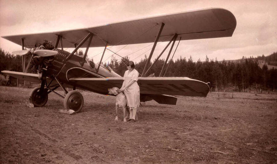 Golda Stonebraker holds a dog by the collar while standing near the airplane at the Stonebraker Ranch in the Chamberlain Basin.