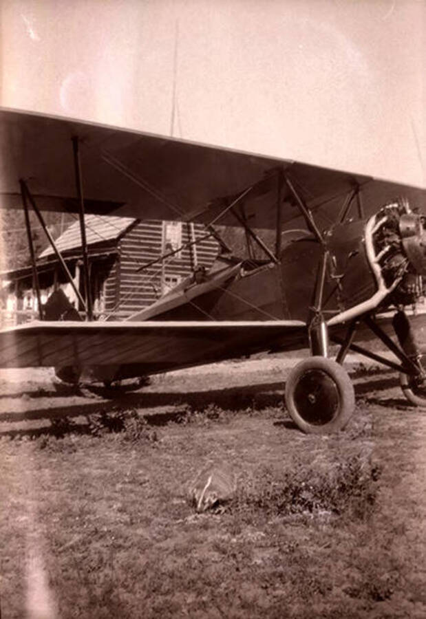 An airplane sits in front of the Stonebraker homestead. A badger can be seen in the foreground of the photograph.
