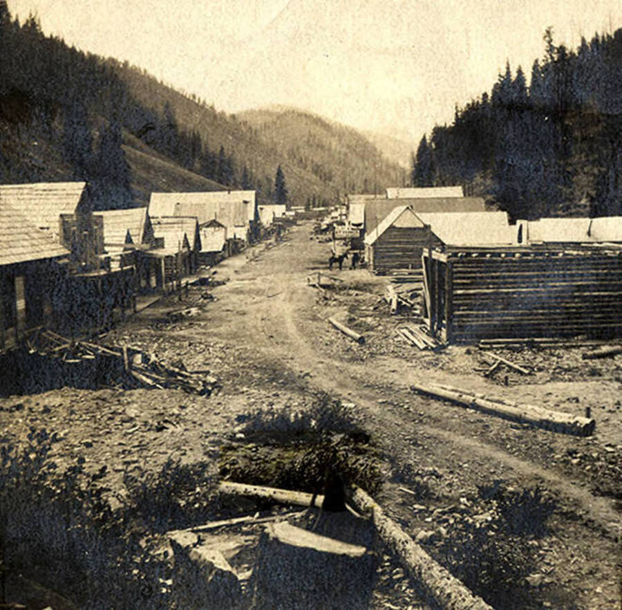 A street view of the mining town Roosevelt, near Thunder Mountain during the height of the gold rush. Wooden buildings line the street.