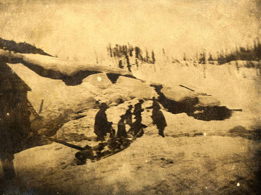 Men transport a cam shaft on a toboggan through the snow for the Dewey Mill near Thunder Mountain.