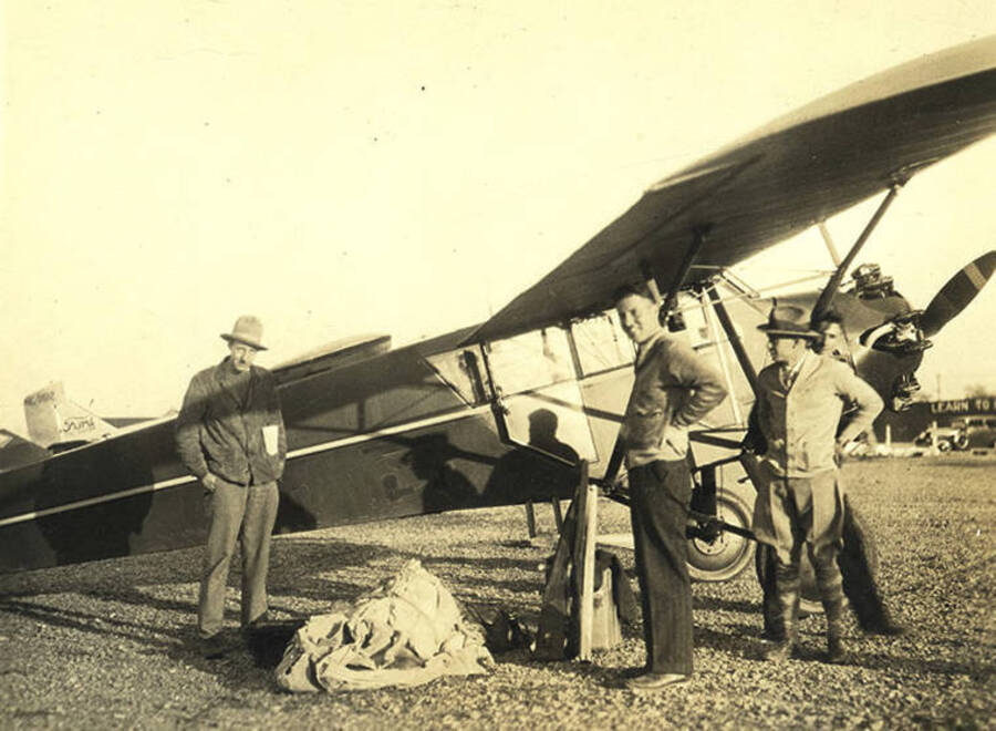 Pilot Nick Mamer (center) and three unidentified men stand beside his airplane at the Stonebraker Ranch.