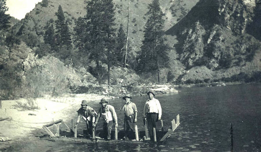 Four men in half-submerged scow on the Clearwater River south of Stites, Idaho.