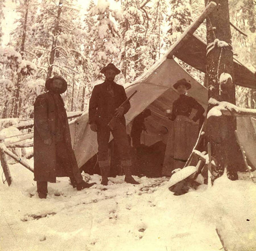 Two men and one woman pose near a tent camp in the snow on the Fourth of July. Jim Moore may be on the left; the woman may be Viola Lamb.