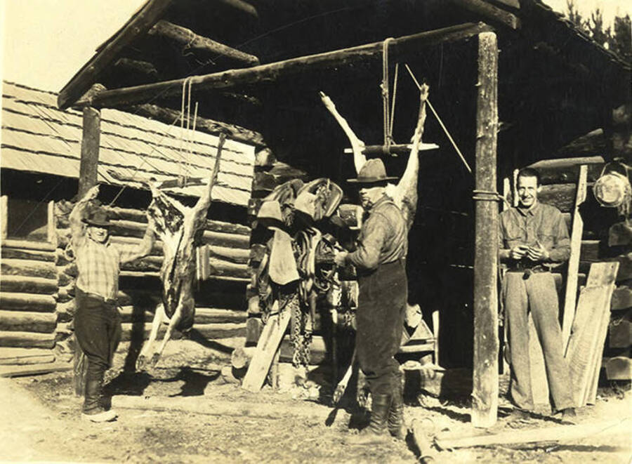 W. A. Stonebraker (middle), pilot Nick Mamer (right), and an unidentified man process deer outside the Stonebraker Ranch.