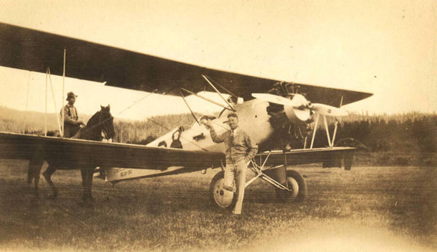 Pilot Nick Mamer (of Spokane, Washington) stands next to his airplane in the Stonebraker Ranch meadow. The airplane was a consolidated fleet with the National Guard. An unidentified man on horse back stands near the airplane.