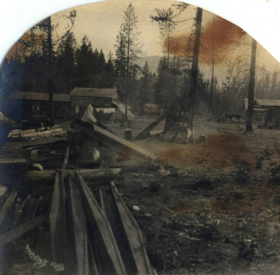 Log cabin buildings and construction equipment sit in a forested area.