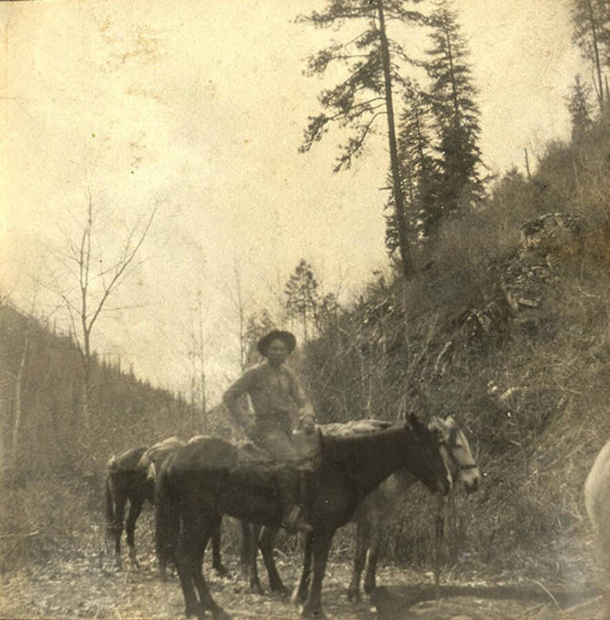 Sumner Stonebraker sits upon at horse. More horses in background.