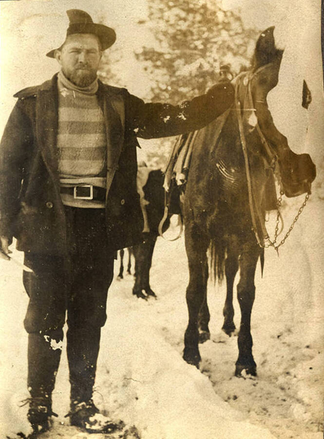 A man holds the reigns of a horse in the snow near Roosevelt, Idaho.
