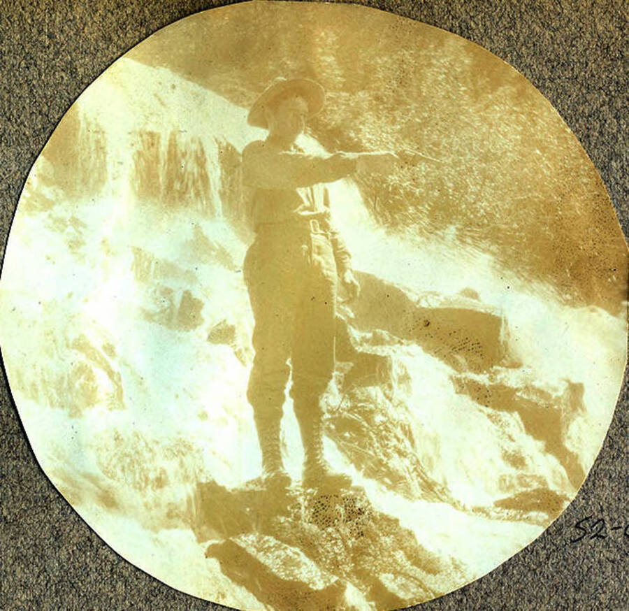 A man stands on a rock in stream aiming a pistol near Buffalo Hump, Idaho.