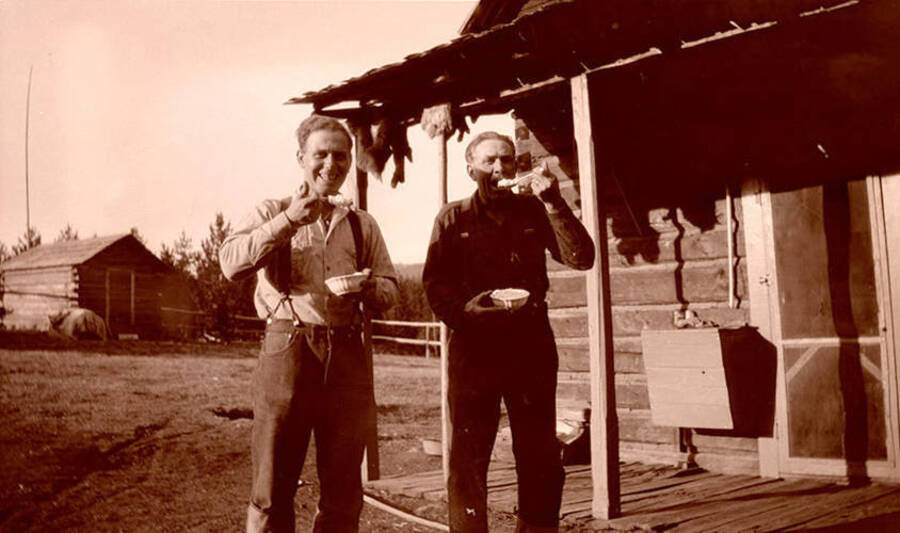 Pilot Nick Mamer (left) and Al Stonebraker (right) eat from bowls on the porch of Stonebraker Ranch.