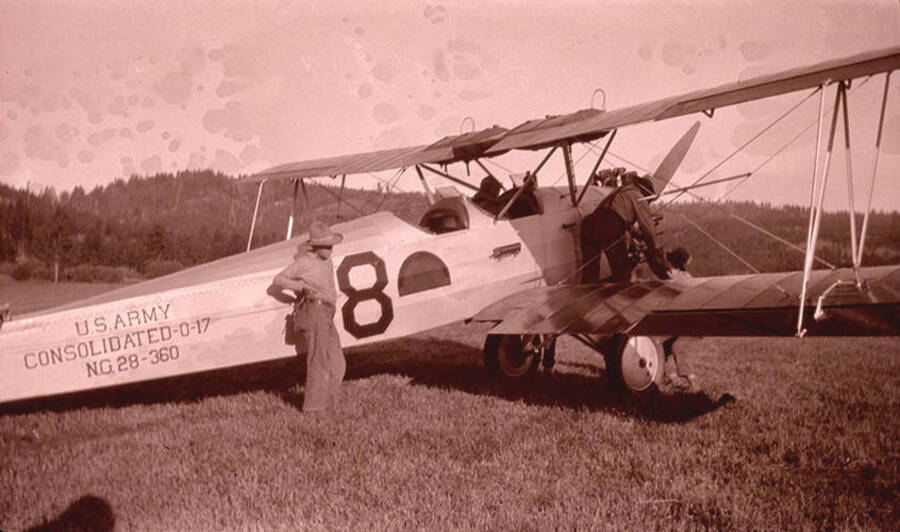 Adolph (Bill) Stonebraker, left, stands near a National Guard airplane (U.S. Army Consolidated 0-17 NG 28-360) while pilot Nick Mamer packs the aircraft. The aircraft is parked in the Chamberlain Basin meadow near the Stonebraker Ranch.