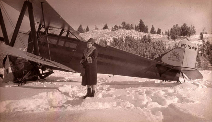 Golda Stonebraker stands in the snow beside seven passenger Zenith airplane at Stonebraker Ranch in the Chamberlain Basin. The pilot was A. A. Bennett.