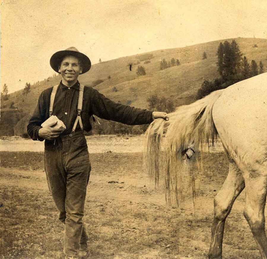 Sumner Stonebraker holding the tail of a Whitey the horse.
