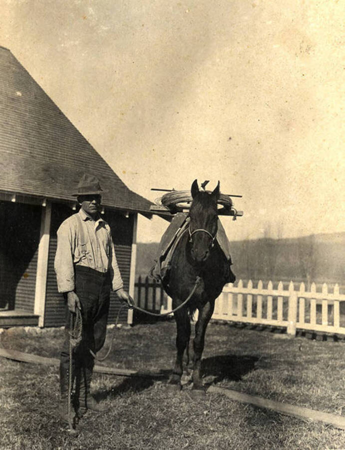 Stonebraker holds the reigns of a horse outside of the homestead. Outside the Stonebraker Ranch in the Chamberlain Basin