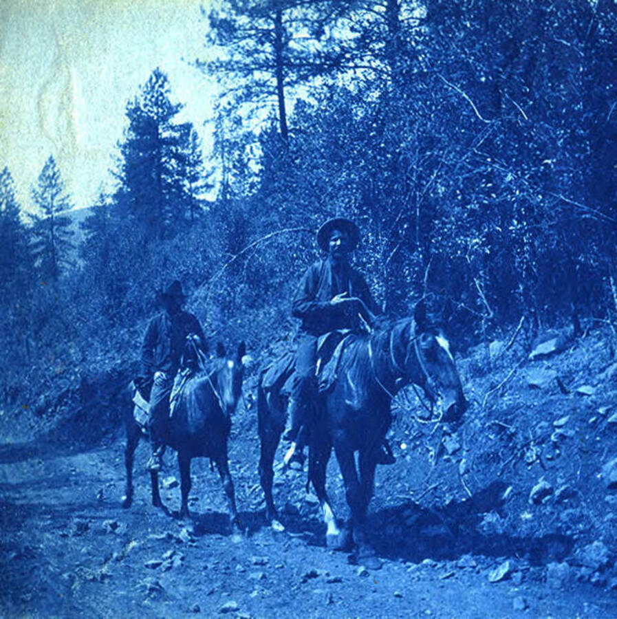 Two men ride on horseback. The photo caption reads: 'On the way.'