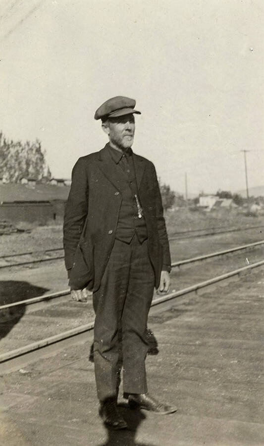 Male train conductor stands by the train tracks.