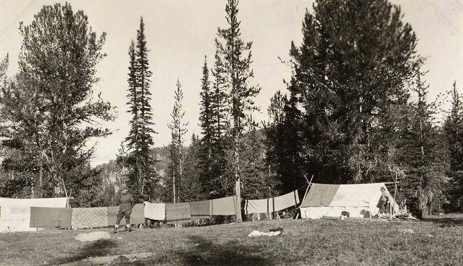 Men near a tent and a clothesline with laundry on the Juno Group of Claims property near Thunder Mountain.