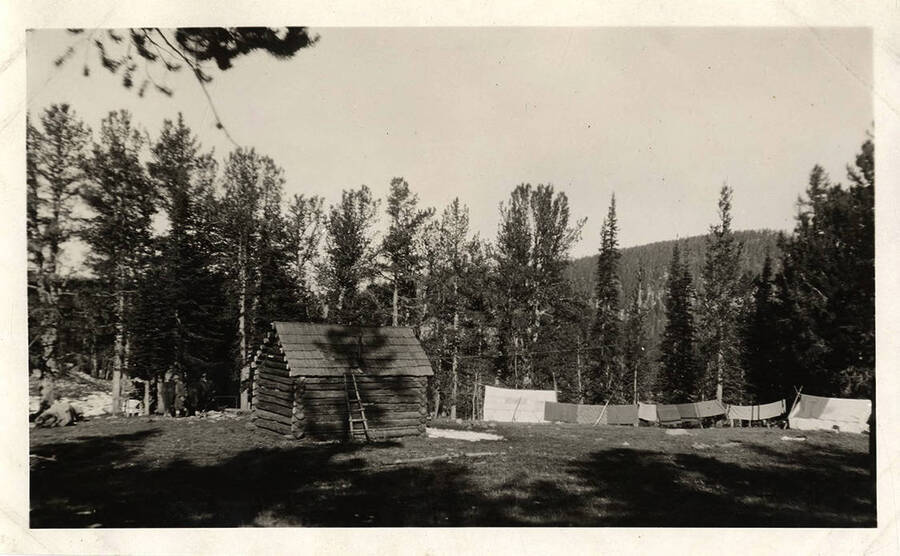 A log cabin is surrounded by tents and laundry hanging on a clothesline at the Stonebraker's Juno Group of Claims property near Thunder Mountain.