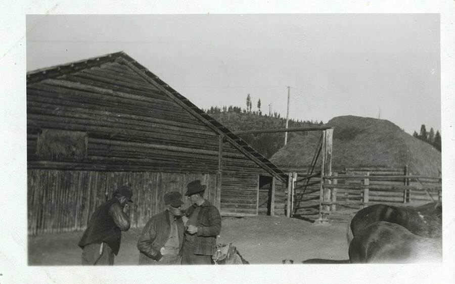 Three men in hats stand inside of a horse corral at the Stonebraker Ranch.