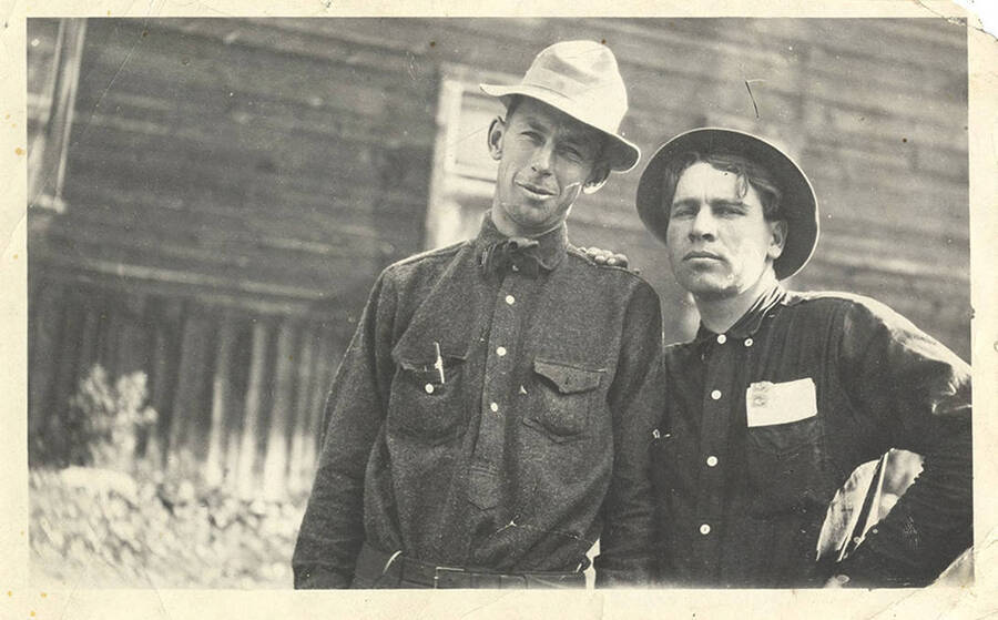 Sumner Stonebraker (right) poses with an unidentified man near the exterior of a building. The photo caption reads: 'Honey get your gun.'