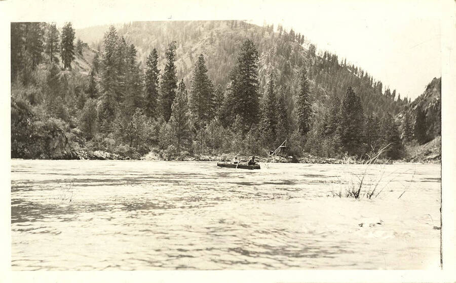 Skiff with two men rowing across the river.