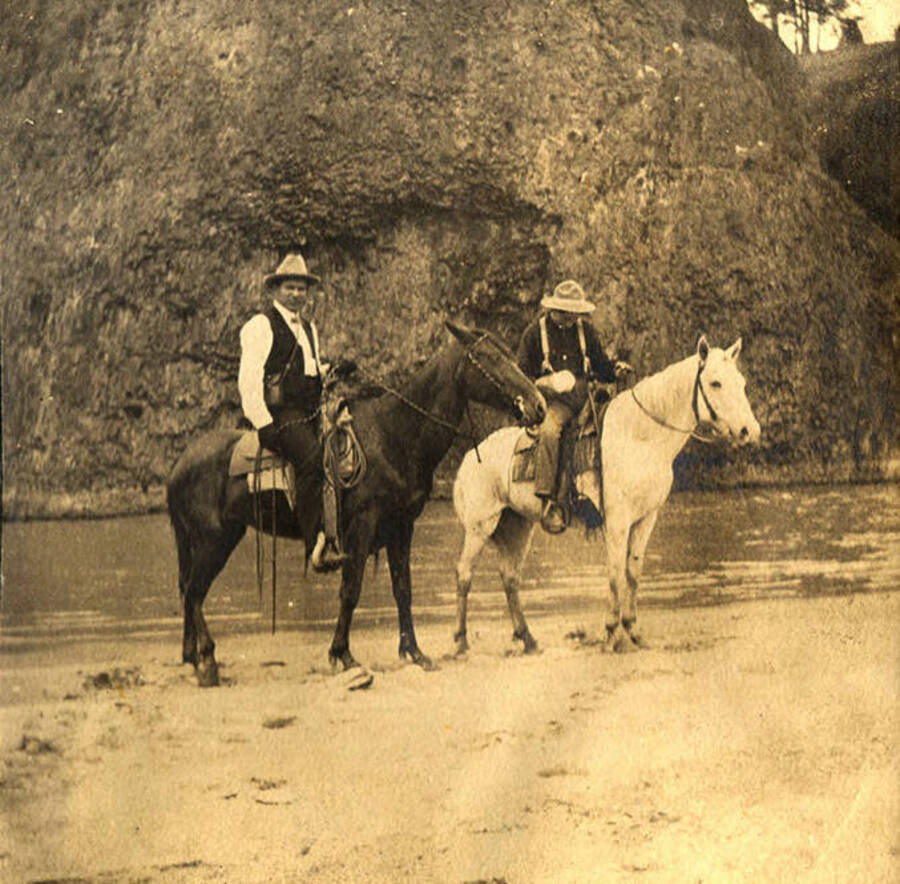 Men on horseback posed next to the Clearwater River.