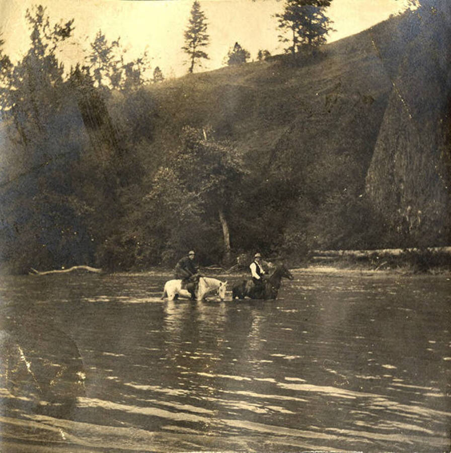 Two men on horseback crossing the Clearwater River.
