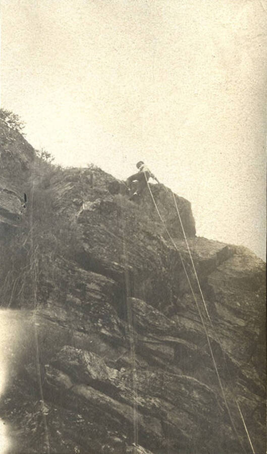 Man climbing at top of rocky canyon.