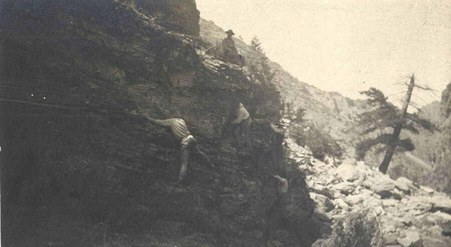 Five men cautiously scale the edge of a rocky canyon.