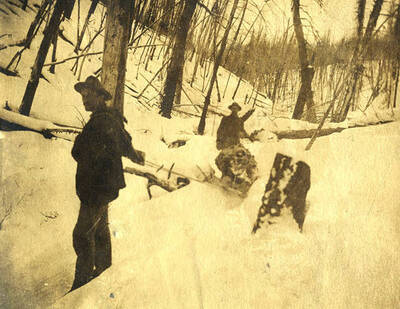 Two men pull a sled through the snow.