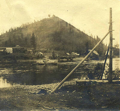 Ferry passes down the river with homes in the background.