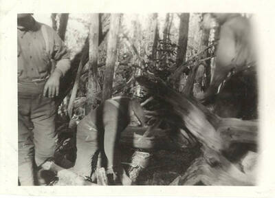 Three men among downed trees.