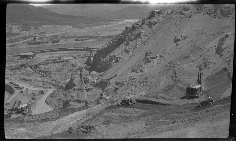 Photo of construction machinery on the side of a hill at Coulee dam. Machinery can be seen at several different working sites in the photo.