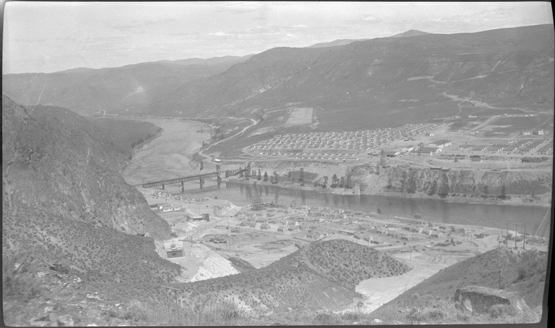 Photo overlooking a majority of, if not all of, a town nearby Coulee Dam. A bridge connecting both sides of the river is visible, and there are houses and buildings on both sides of the river.
