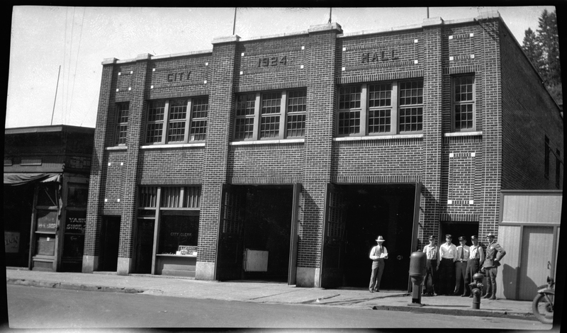 Photo of the Wallace, Idaho City Hall. The building reads "City; 1924; Hall." The large French doors of the building are open, and six unidentified men in uniforms stand outside to post for a picture.