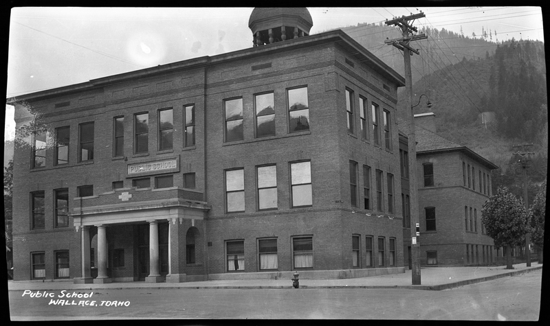 Photo of a public school building in Wallace, Idaho. The building is three stories tall and there is a sign that reads "Public School" above the front doors.