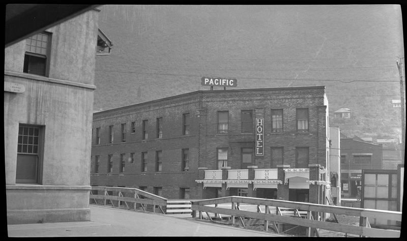 Photo of the back of the Pacific Hotel in Wallace, Idaho. There are two signs on the building, one that reads "Pacific" and the other reads "Hotel." There appears to be a balcony attached to the second floor of the building.