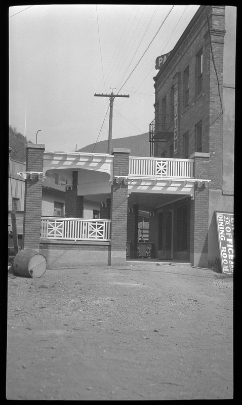 Photo of the rear entrance to the Pacific Hotel. The entrance to the building is covered, and it appears that the cover also serves as a balcony for the second floor.