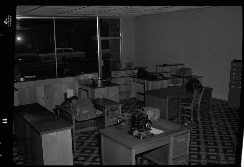 Photo of the interior of Citizens Utility Company office. There are several desks within the room, some of which have phones and typewriters on them.