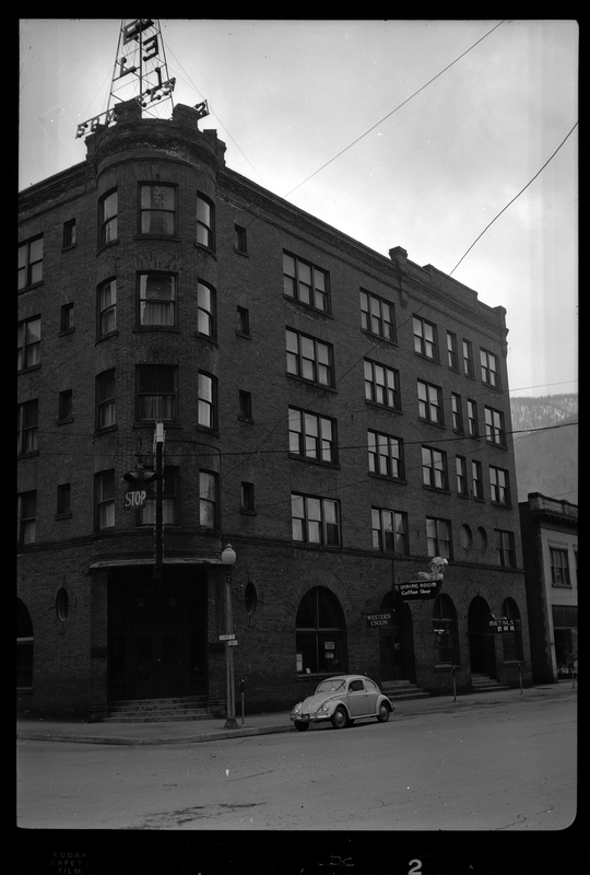 Photo of the right side of the building in which Samuel's Hotel is in, as well as the Western Union and Metal Bar. The building itself sits on the street corner and appears to be at least four stories tall. There is a car parked on the road next to the building.