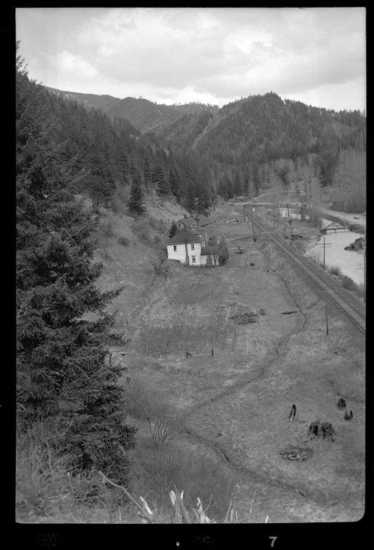 Photo of what appears to be a house in the distance. Described as "Standard Dairy, E. F. Gentry." The photo was taken from a higher elevation and looks down at the building from the side. There is a river that runs near by the building.