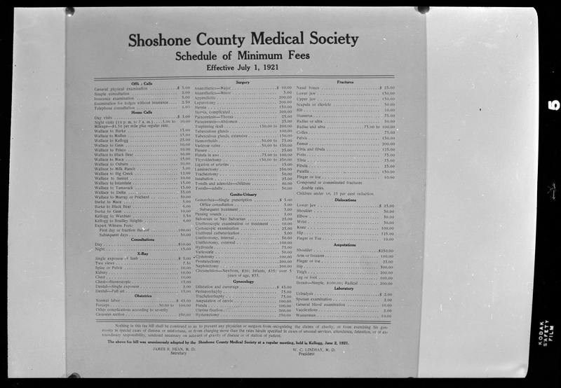 Photo of the Shoshone County Medical Society Schedule of Minimum Fees sign. The prices are effective as of July 1st, 1921 as written on the sign. The prices for medical treatments are listed and organized by type.