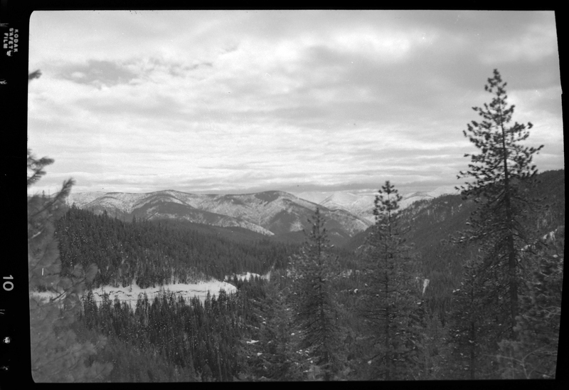 Photo overlooking Dobson Pass, Idaho. Previously described as "Dobsone Parr Outdoor scenes." Trees cover the mountains and there is visible snow on the ground and trees.