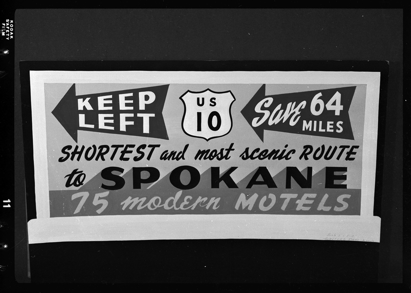 Photo of a sign that gives directions to access U.S. Highway 10 to Spokane. The sign reads, "Keep left; US 10; Save 64 Miles; shortest and most scenic route to Spokane; 75 modern motels."