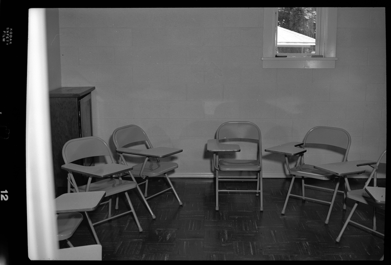 Photo of a group of metal chairs with desk space arranged in a semi circle in a small room. They are within an Episcopal Church in Wallace, Idaho.