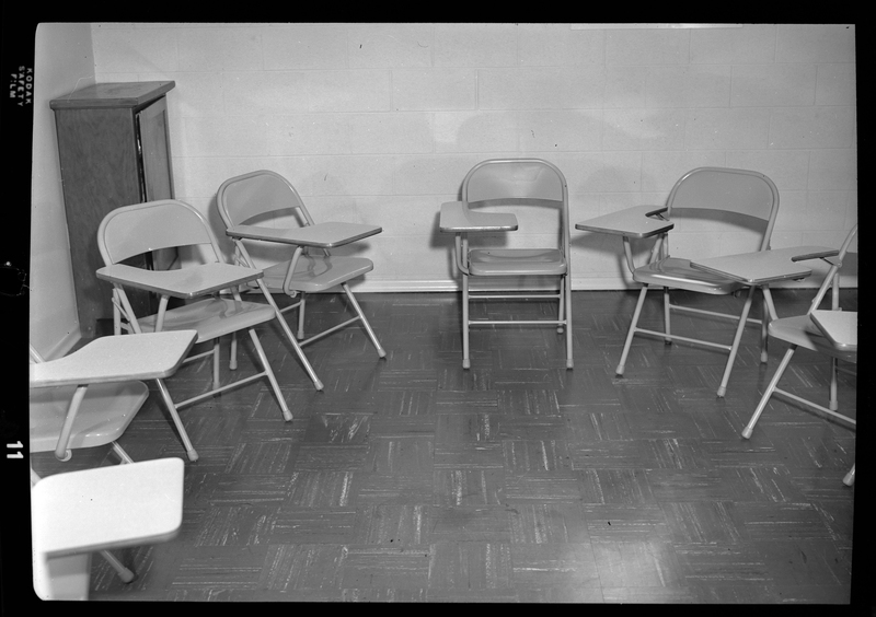 Photo of a group of metal chairs with desk space arranged in a semi circle in a small room. They are within an Episcopal Church in Wallace, Idaho.