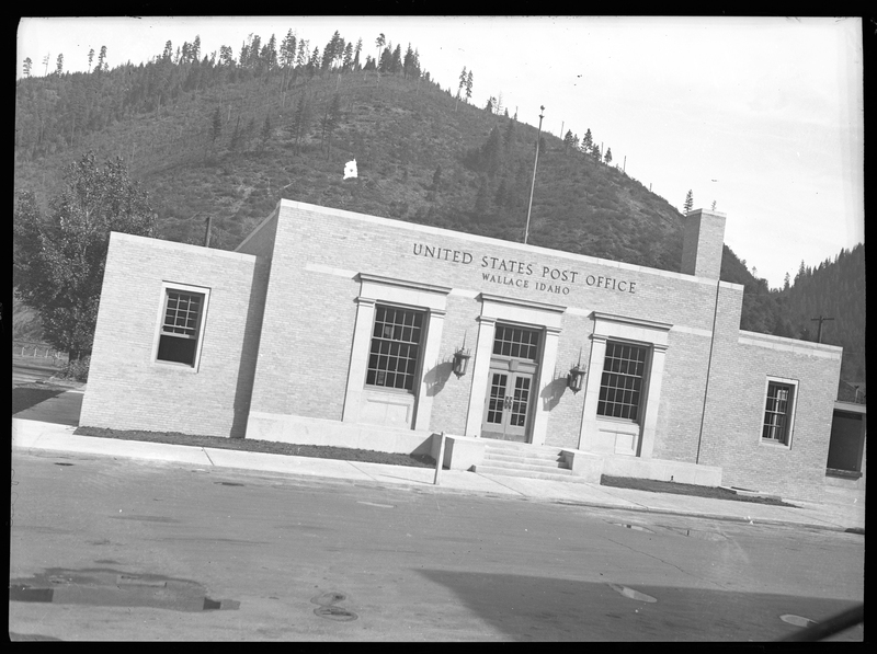 Photo of the exterior of the Wallace Post Office building. The signs on the building read "United States Post Office; Wallace Idaho." 