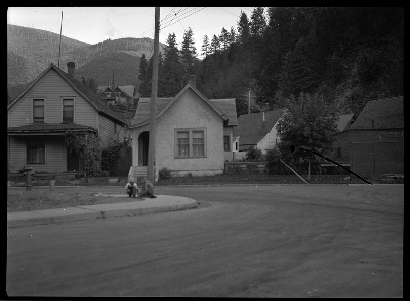 Photo of a home in Wallace, Idaho taken for Household Magazine. The home is small with a yard on the side of it and appears to only be one story tall. There are two kids playing on the sidewalk between the house and the photographer.